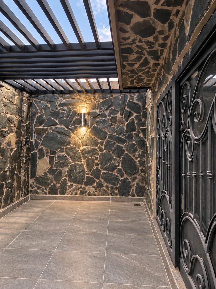 Patio con muro de piedra, p�rgola y reja forjada
